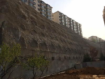 The picture shows a bare cliff, with trees on the left corner.