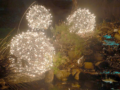 There are three spherical hexagonal wire mesh with many lights on them.