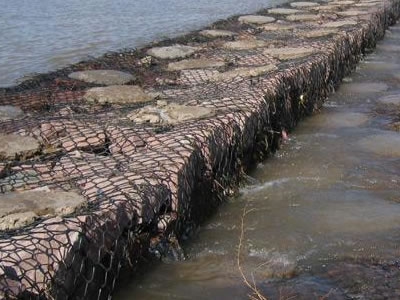 Water flow through stone spacing of gabion basket.