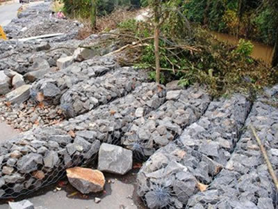 Galvanized gabion sacks full of stones are placed on roadside.