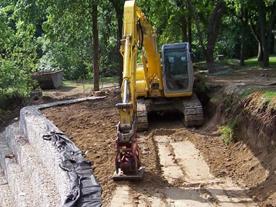 A yellow machine is compressing soil.