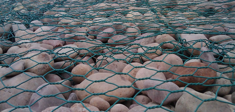 Many green PVC gabions filled with stones are linked together.