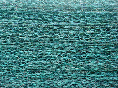There are many green PVC coated hexagonal wire mesh panels placed on ground.