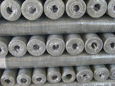 There are many galvanized hexagonal wire mesh rolls wrapped with film.