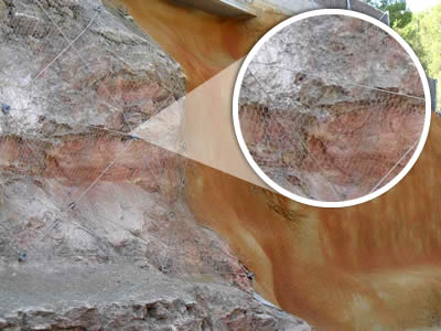 A rustic concrete shows in the right part of the slope, hexagonal wire mesh netting reinforced by anchor lines show itself in the left part.