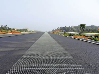 In the middle of a highway road, a roll of hexagonal wire mesh has been extended out.