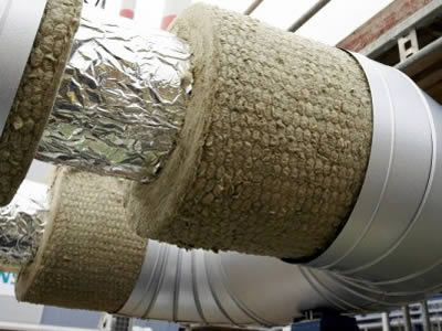 From the middle of a pipe, aluminum foil, hexagonal metal mesh covered rock wool blanket shows.