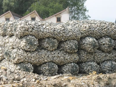 PVC coated gabion sack full with stones are placed in clearing.