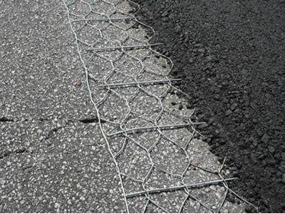 A layer of hexagonal wire mesh and asphalt have been applied onto the original cracking asphalt road.