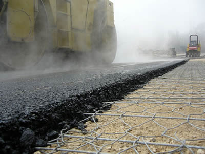 A part of hexagonal shows itself from the unfinished asphalt construction part on a road.