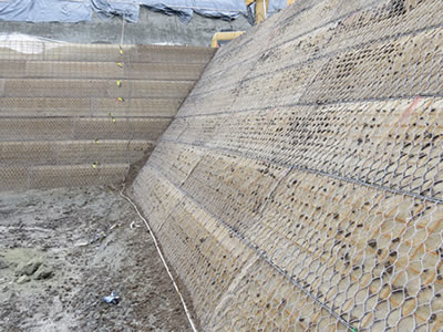 Green hexagonal terramesh has made a two-faced slope, on the front face and right side face.